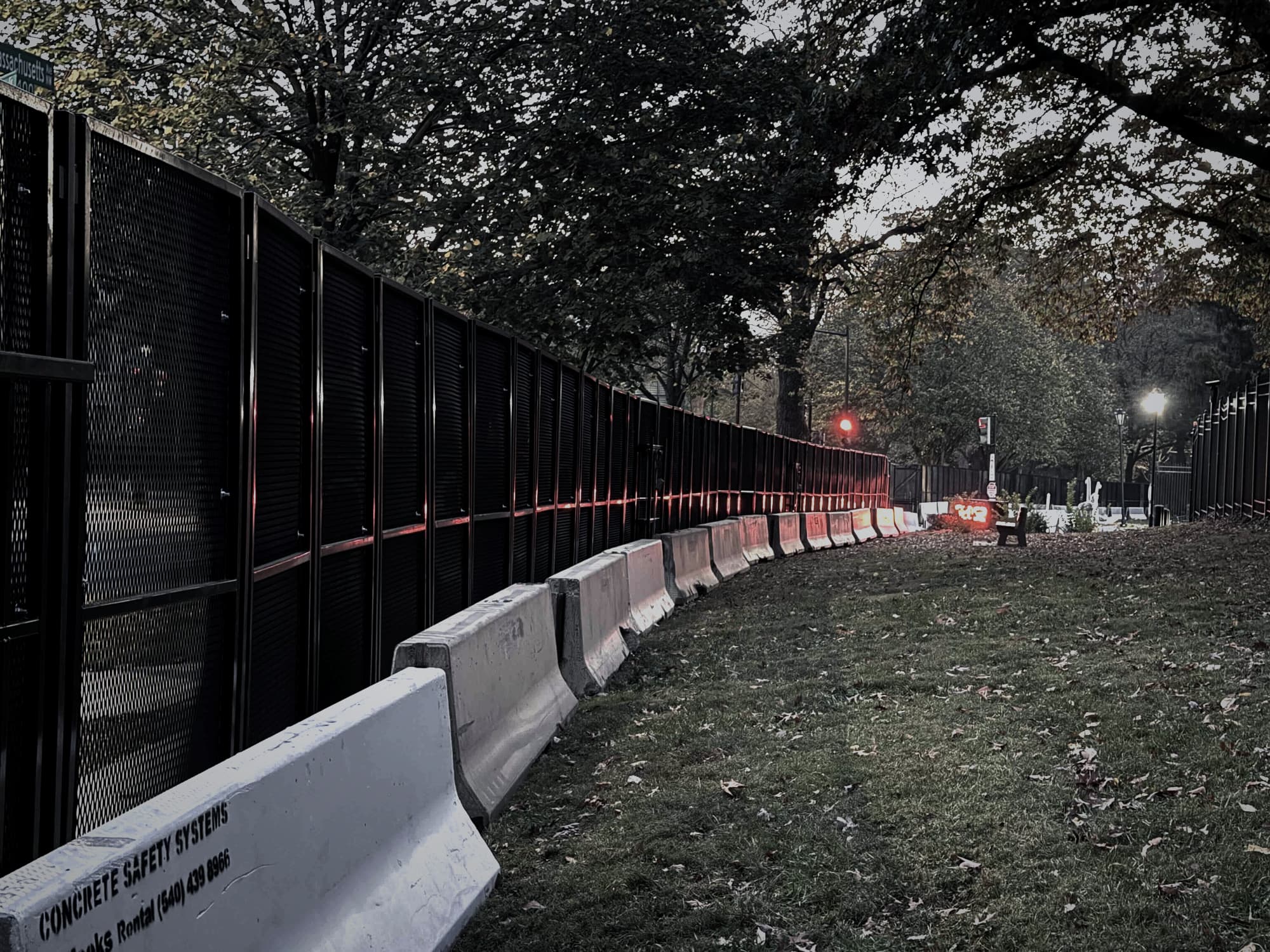 Illuminated security perimeter at night with concrete barriers along the fence line